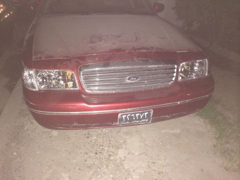 1998 Ford Crown Victoria - Front view of a dusty red 1998 Ford Crown Victoria showing the grille and headlights.