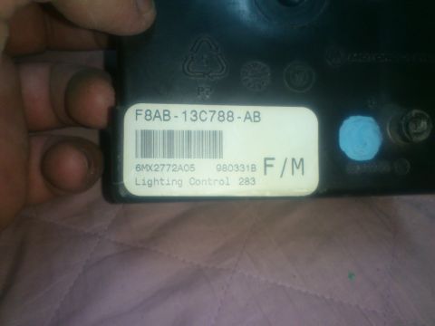 1998 Ford Crown Victoria - A hand holds a lighting control module with a part number and description visible on its label.