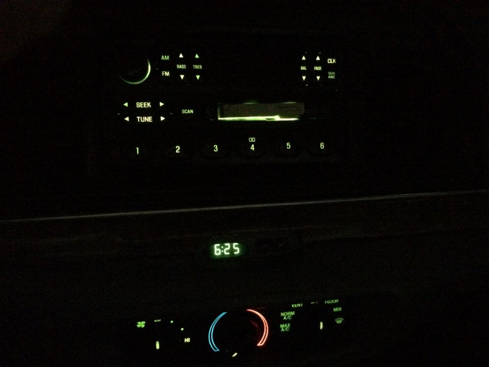 Car interior showing glowing radio and climate controls at night