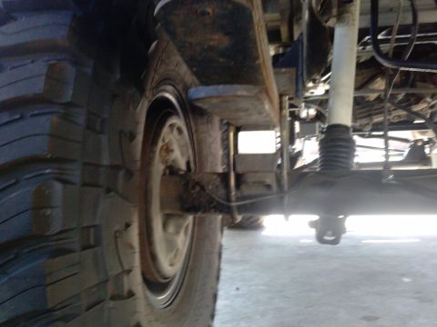 1995 Ford Bronco - Undercarriage view of a vehicle's suspension system, focusing on the rear axle and tire.