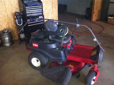 1982 Ford Bronco - A Toro zero-turn lawnmower with a windshield is parked indoors next to a toolbox.