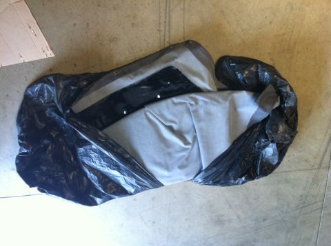 1982 Ford Bronco - A car's convertible top is stored in a protective black plastic bag.