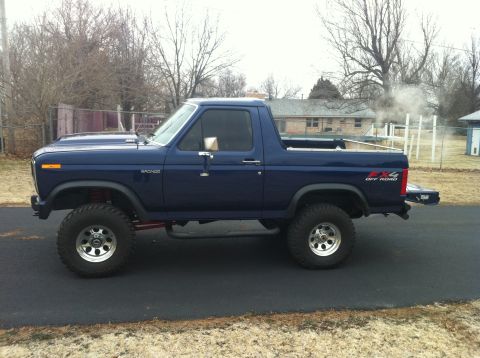1982 Ford Bronco - This lifted blue Ford Bronco has off-road tires and a custom exhaust emitting smoke.