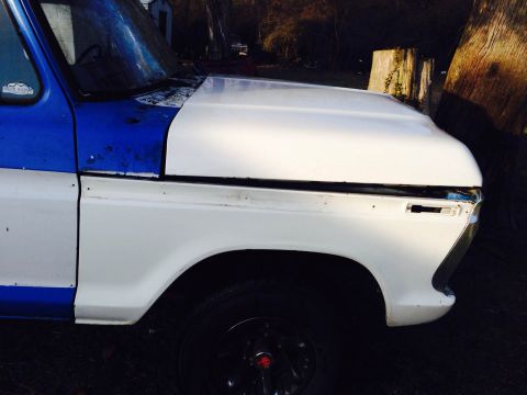 1979 Ford Bronco - The front section of a two-tone Ford truck is shown, with visible wear and tear on the paint.