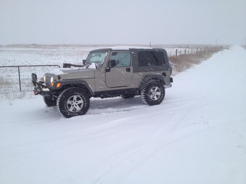 2005 Jeep Wrangler - A Jeep Wrangler navigates a snow-covered rural road during a winter storm.