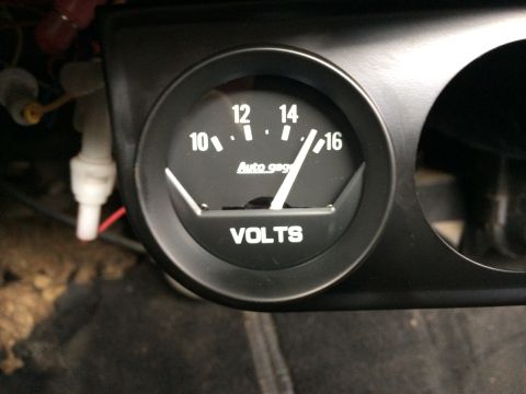 1964 Ford Ranchero - A close-up view of a black Auto Gage voltmeter gauge with white markings and a needle indicating 15 volts.