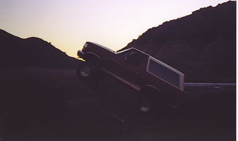 1992 Ford Bronco - This Ford Bronco is shown navigating a steep, dusty incline during daylight hours.