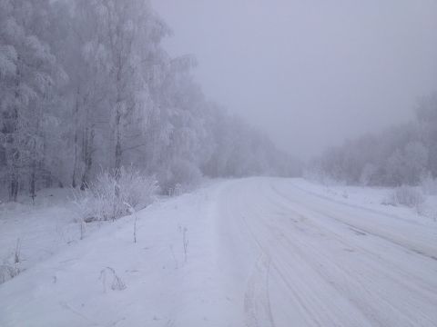 1987 Ford Bronco - A desolate, snow-covered road winds through a forest where trees are heavily coated in frost and ice.