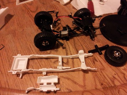 1995 Ford Bronco - The chassis and components of a remote-controlled vehicle are spread out on a wooden surface.