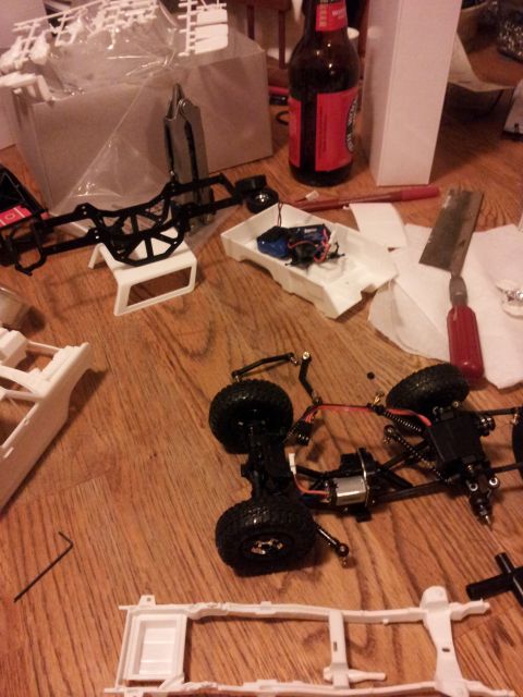 1995 Ford Bronco - Model car parts and chassis are laid out on a wooden table, suggesting assembly is in progress.