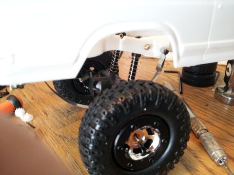 1995 Ford Bronco - Detail of an RC car's suspension system and wheel assembly, with tools nearby.