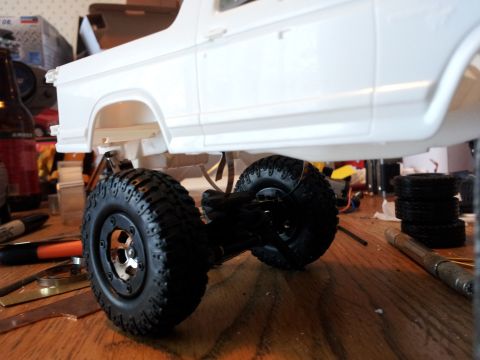1995 Ford Bronco - This is a close-up view of a model car's chassis and wheels, with the body unpainted.