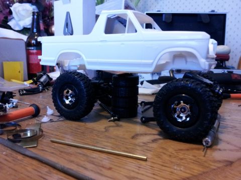 1995 Ford Bronco - Model car parts laid out on a wooden surface, including a Bronco body and chassis.