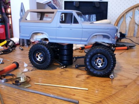 1995 Ford Bronco - Model car chassis and body shell on a workbench with various tools and parts.