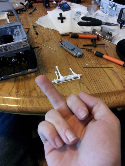 1995 Ford Bronco - A person is assembling a model vehicle, with various parts and tools spread across a wooden table.