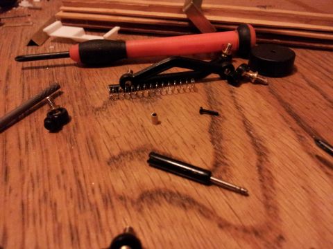 1995 Ford Bronco - Various model car components and tools are laid out on a wooden table, suggesting assembly or repair.