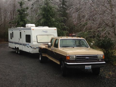 1988 Ford F-350 - A Ford pickup truck tows a travel trailer in a wooded area with icy trees.
