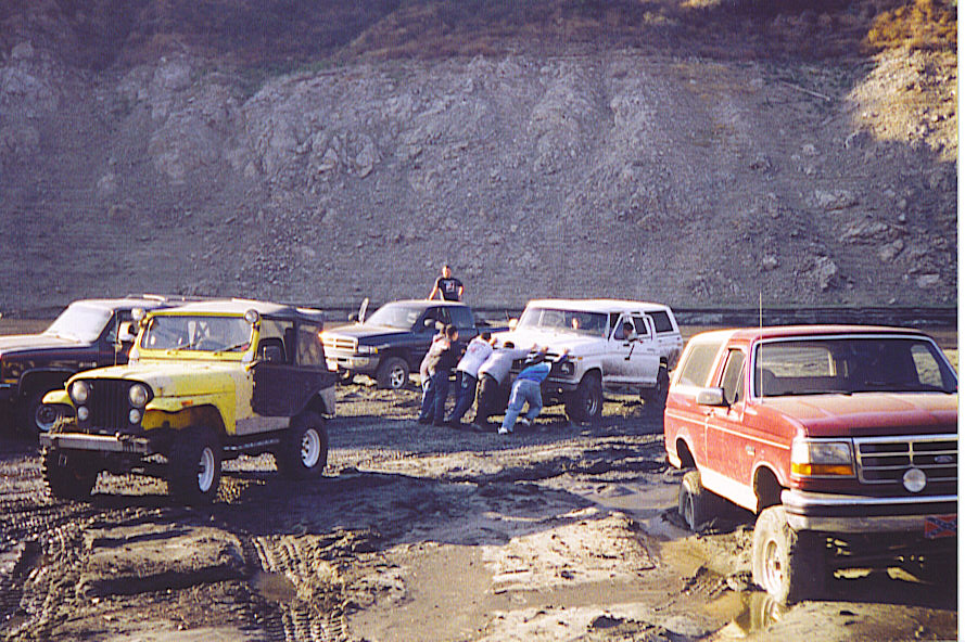 1992 Ford Bronco and other off-road vehicles stuck in mud, people pushing