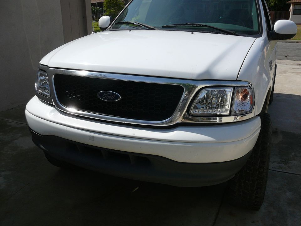 White Ford truck front end with chrome grille and headlights