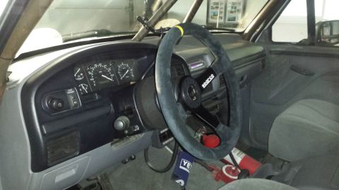 1996 Ford Bronco - The interior of a 1996 Ford Bronco shows a Sparco steering wheel and a roll cage, suggesting a racing or off-road modification.
