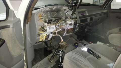 1996 Ford Bronco - The interior of a vehicle is shown with the dashboard disassembled, exposing wires and internal parts.