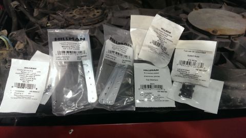 2000 Mercury Grand Marquis - A collection of assorted hardware parts, such as mending plates and speed nuts, are laid out on a surface.