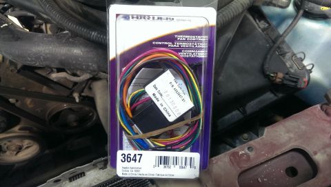 2000 Mercury Grand Marquis - A new thermostat fan control wiring harness is shown in its packaging, placed within an engine bay.