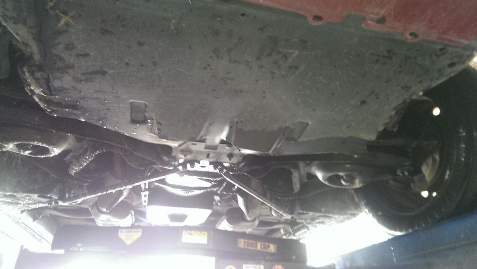 Underside view of a car on a lift, showing the drivetrain and suspension components