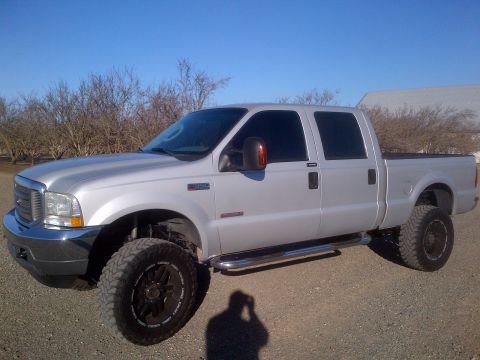 1985 Jeep CJ7 - Silver Ford F-250 Super Duty pickup truck with aftermarket wheels and lift kit.