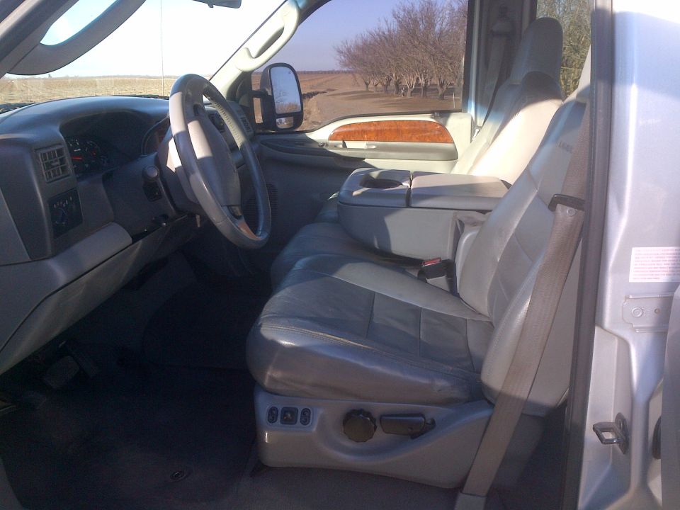 Interior of a truck showing the driver's seat, dashboard, and center console. Wood trim accents are visible on the door