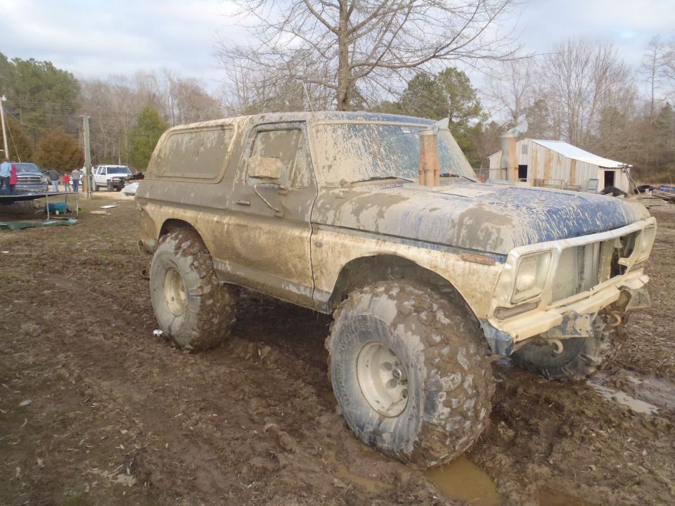 Mud-covered 1978 Ford Bronco with large tires stuck in mud