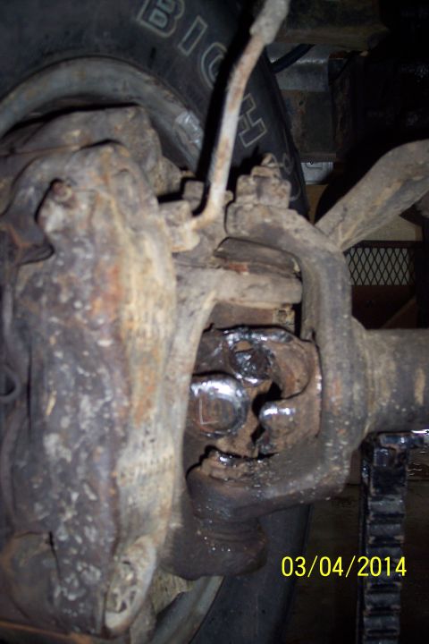 1973 Ford F-250 - Close-up view of a rusty front axle knuckle and U-joint assembly.
