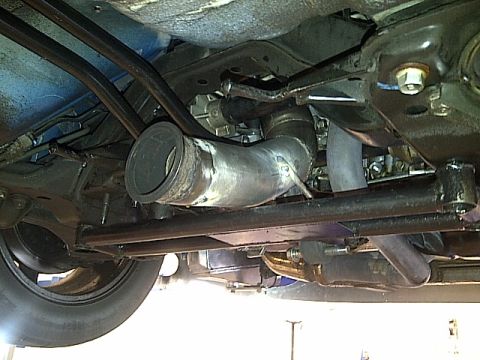 1995 Ford Probe - The underside of a vehicle displays a custom exhaust system and various mechanical parts.