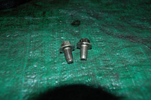 1994 Ford Bronco - Two bolts are shown resting on a green, textured surface, possibly a tarp.
