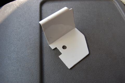 1994 Ford Bronco - A small, gray plastic trim clip is shown against a textured gray interior surface.