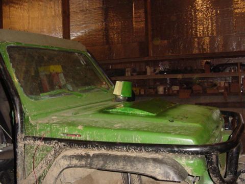 1992 Ford Bronco - Customized green off-road vehicle with a prominent hood scoop and roll cage, seen in a workshop.