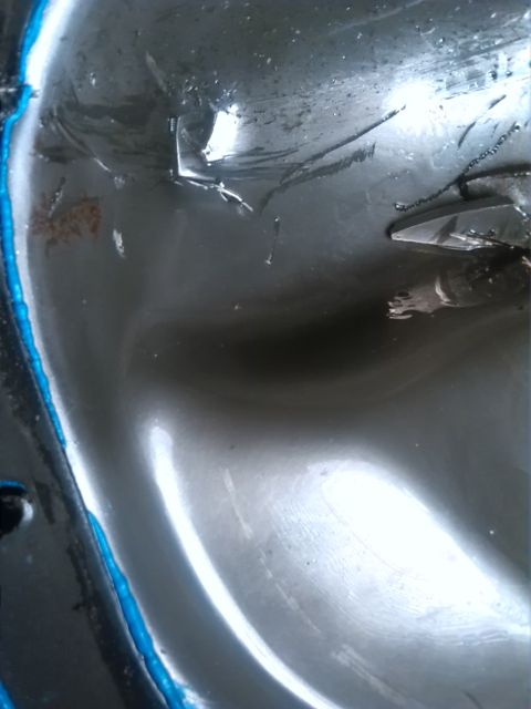 1992 Ford Bronco - Close-up of a damaged engine oil pan with visible metal fragments and blue sealant.