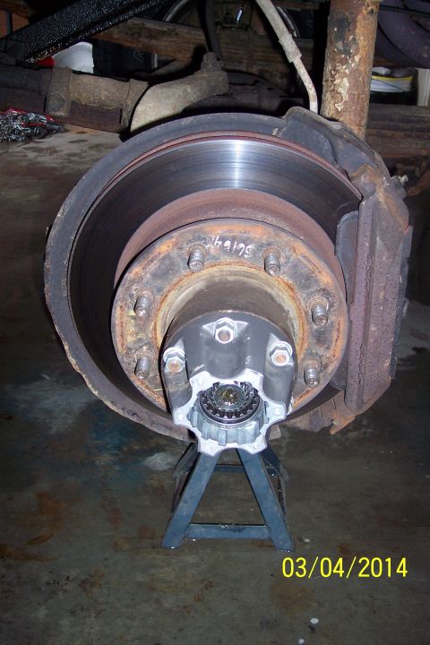 1973 Ford F-250 - A vehicle's front wheel hub and brake assembly are shown, supported by a jack stand.