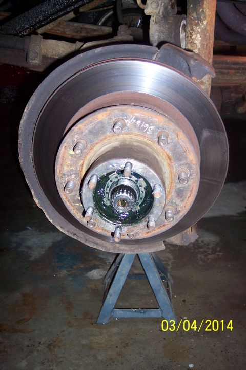 1973 Ford F-250 - A vehicle's wheel hub and brake rotor assembly is shown supported by a jack stand, with visible grease in the hub.