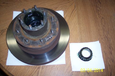 1973 Ford F-250 - A greased wheel hub assembly and a bearing are laid out on a wooden surface.