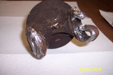 1973 Ford F-250 - A close-up view of a heavily corroded metal component with visible, rough welding repairs.