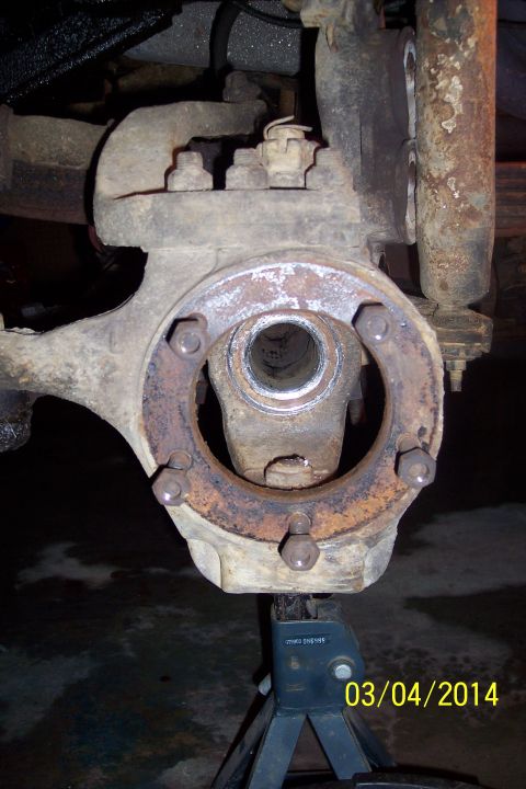 1973 Ford F-250 - Close-up of a worn front knuckle joint assembly, supported by a jack stand.