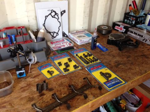 1996 Ford Bronco - Various engine components and tools are laid out on a wooden workbench, ready for assembly or repair.