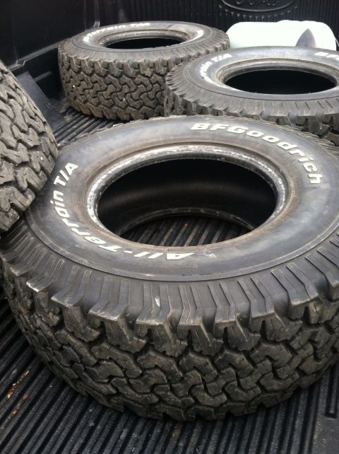 1979 Ford Bronco - Four BFGoodrich All-Terrain T/A tires are piled in the back of a pickup truck.