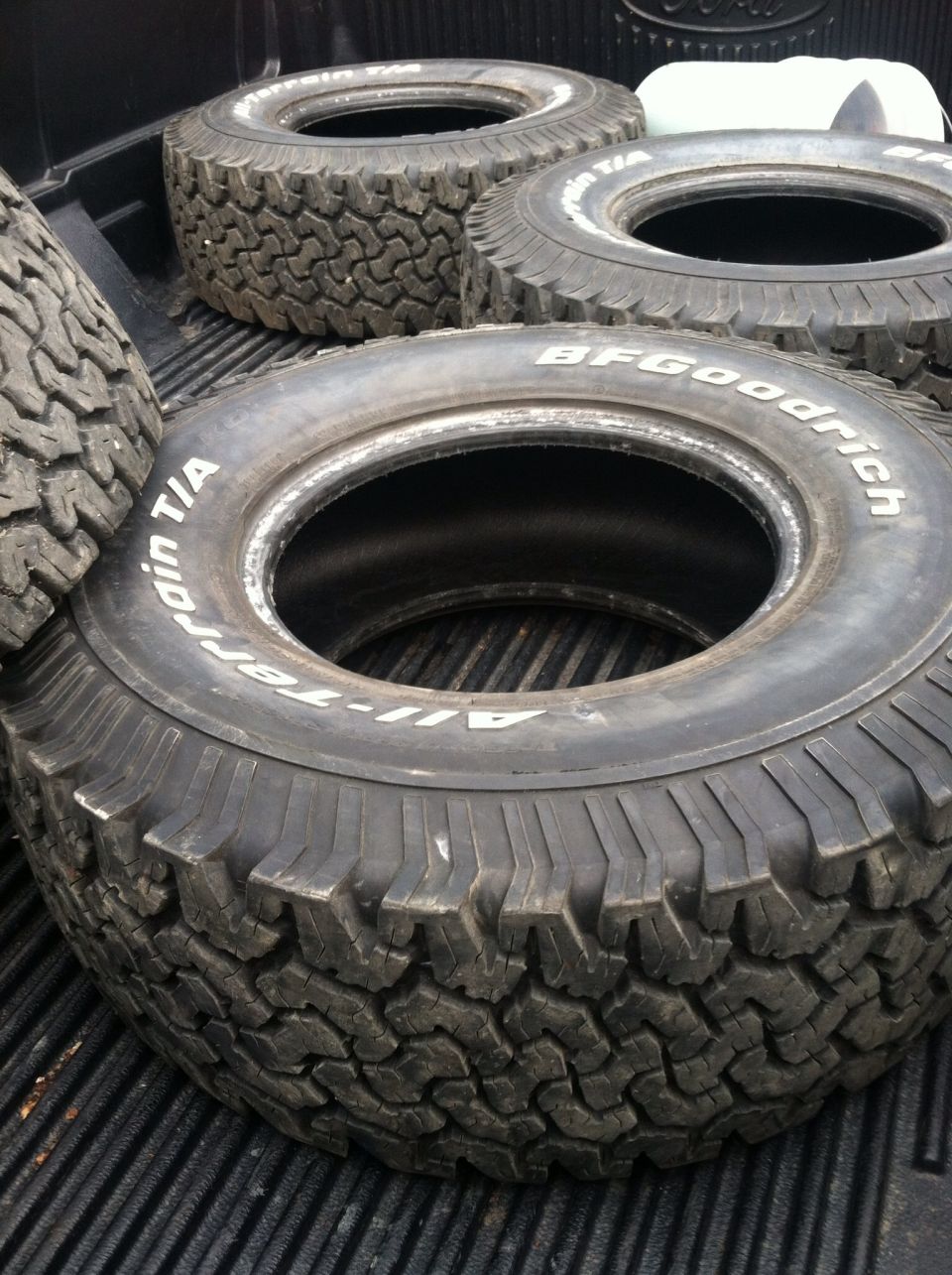 Several BFGoodrich All-Terrain T/A tires stacked in the bed of a truck