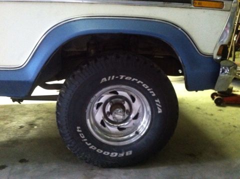 1979 Ford Bronco - Close-up of the front passenger side wheel well and tire of a white and blue 1978 Ford Bronco.