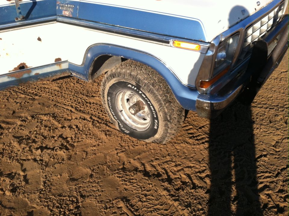 1979 Ford Bronco front corner with blue fender flares and chrome bumper in dirt