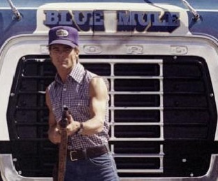 1979 Ford Bronco - A man poses in front of the grille of a large truck that reads 'BLUE MULE'.