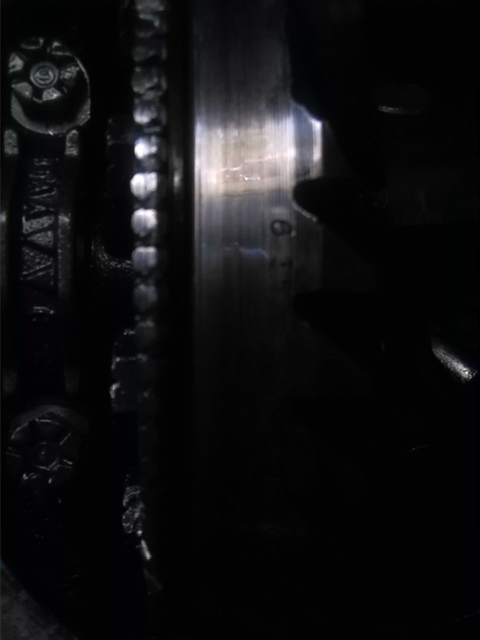 Close-up of a metal gear and bolt heads, with a partial serial number visible