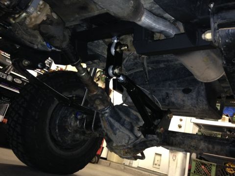 1987 Suzuki Samurai - Close-up view of aftermarket suspension components, including an anti-wrap bar, installed on a vehicle's rear axle.